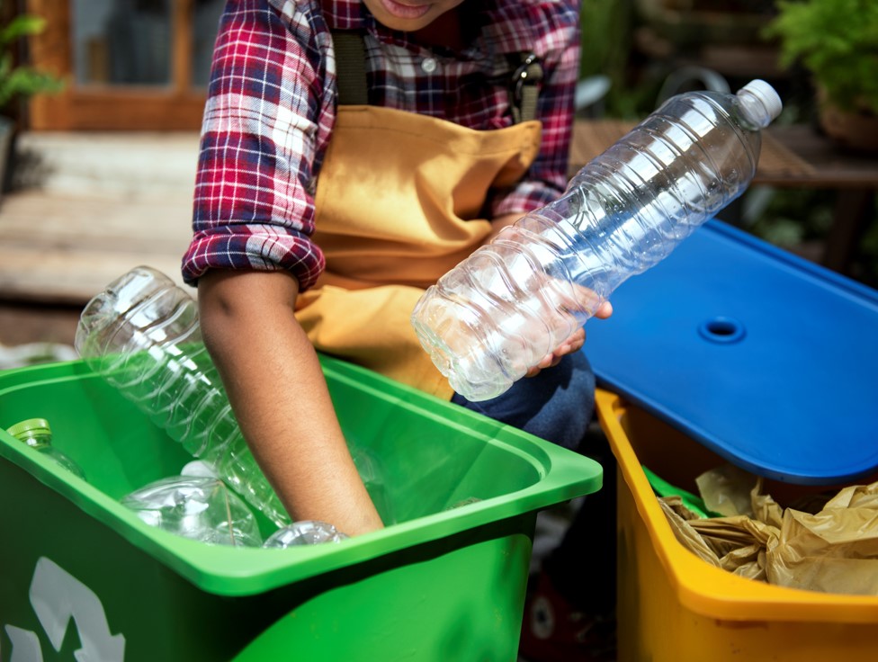 widok na rękę wkładająca do śmietnika plastikową butelkę